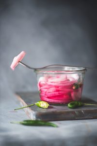 Khatta pyaaz is pickled onions.Onion pickled in vinegar or lemon juice ending in beautiful, tangy, sweet onions. A perfect accompaniment with Indian dishes.