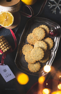 Cream the butter and sugar using an electric blender. This will usually take 8 minutes. Till the mixture gets creamy, fluffy and light. Add Lemon zest and poppy seeds and let it mix. Reduce the speed to 1 and now gradually add the All Purpose Flour and salt.  Once the dough comes together, wrap it in a clingfilm. Flatten it into a disk and refrigerate for 15 to 20 minutes. Remove the dough disks and place them in between two layers of grease proof paper and roll it to a 3mm thick sheet and place it in the refrigerator for 15mins. This will harden the dough and help cut crisp, sharp edges.   Preheat the oven to 180degree. Line the cookie sheet with parchment paper. Cut the cookies using 2"cookie cutter. Place the cut shapes on the cookie sheet with one finger distance and place it in the refrigerator for 15 mins. Bake for 10 to 12 minutes or till they are golden brown and darker at the edges. Leave them on the cookie sheet for a couple of minutes and then transfer them onto a cooling rack. let it cool completely. Store it in an airtight container. For icing the cookies mix the sugar and lemon juice and spread it over the cookies into a thin layer and air dry it. Store it in an air tight container.